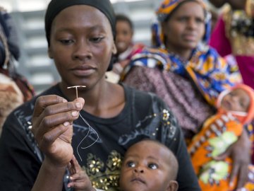 A woman holds up a contraceptive implant during Marie Stopes mobile clinical outreach team visit to a hospital in Rabai, Kenya. June 16, 2014.