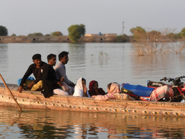 Internally displaced people use a boat to cross a flooded area at Dadu in Sindh province, Pakistan. October 27, 2022. Asif Hassan/AFP via Getty Images