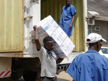 3 workers unload boxes of vaccines from a truck in Bujumbura, Burundi.