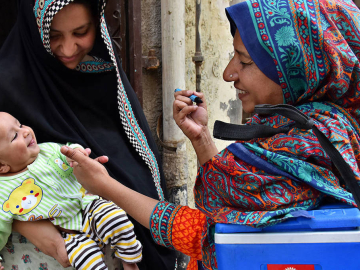 A woman gives a polio vaccine to baby.