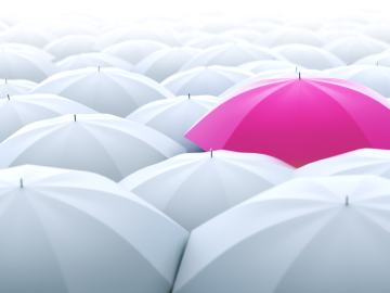 A pink umbrella stands out among many white umbrellas.