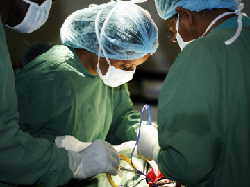 Closeup of a surgeon in green scrubs and her assistants operating on a patient. Universal Images Group Getty