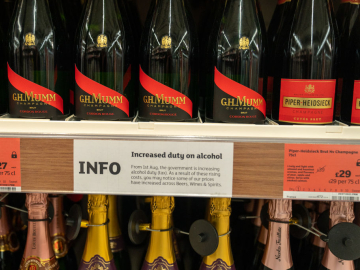 A notice is posted about a rise in duty for alcoholic beverages, between two rows of champagne bottles on store shelves, August 4, 2023 at a Sainsbury's Market in London, England. Robert Nickelsberg/Getty