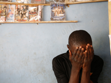 A young man hiding his face in his hands.