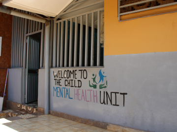Yellow and gray building with the words &quot;welcome to the mental health unit&quot; painted on them.