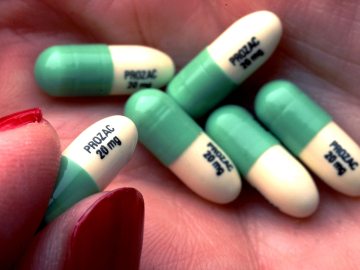 A person holds Prozac tablets in their palm.