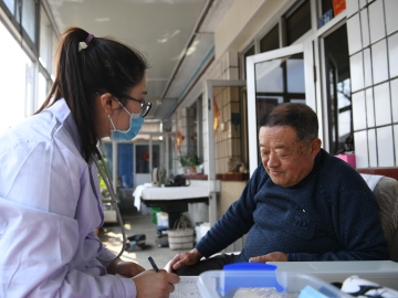 Sun Yi, a village doctor, helps a villager register health information at Qianyang Village, Donggang City, China.