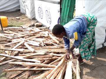 Hellen Anyango sorting a stash of firewood, which she occasionally sells to help support her four children. Nduru camp, Kisumu City, Kenya.