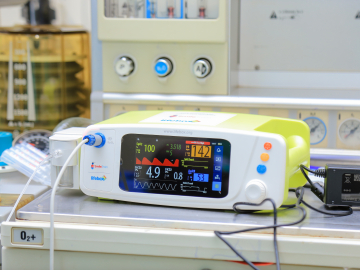 Image of a capnograph surgical monitoring device, a small whie box with a screen displaying vital statistics.