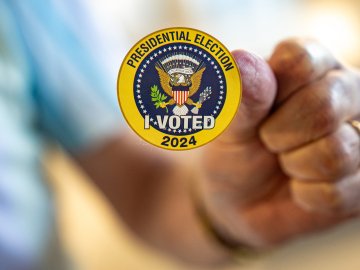 A man holds up a sticker that reads &quot;Presidential Election I Voted 2024&quot; on the first day of Virginia's in-person early voting at Long Bridge Park Aquatics and Fitness Center on September 20, 2024, in Arlington, Virginia.