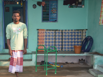 Muthukutti, a 23-year-old man from Surangudi, India, stands outside his home.
