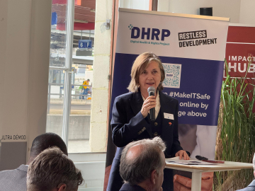 Photo of Professor Meg Davis holding a microphone and speaking before an audience for a sidebar event at the World Health Assembly.
