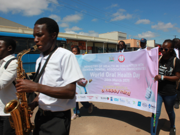 A saxophone player wearing a white t-shirt plays in a parade marking World Oral Health Day in Zambia.
