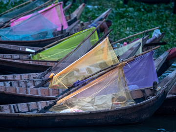 Boatmen sleep inside colorful mosquito nets on their boats on the Buriganga River in Dhaka, Bangladesh.