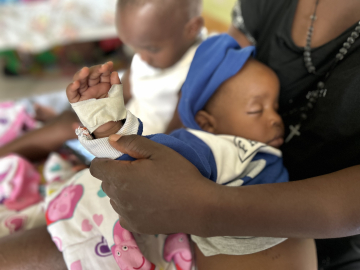 Olivia Nansamba holds her son Melvin’s bandaged, swollen hand as he rests.