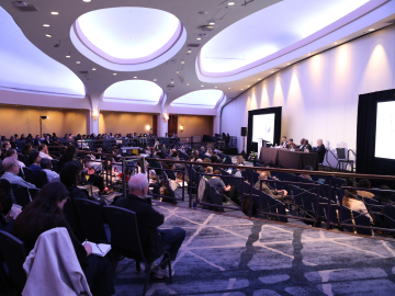 Panelists on the stage in a ballroom at the Washington, DC Hilton hotel, with a view of the audience from behind.