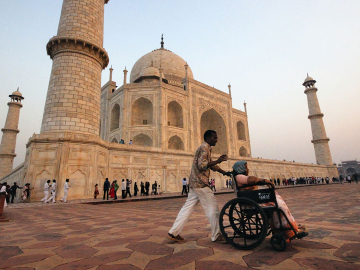 A man pushes a woman in a wheelchair at the Taj Mahal in Agra, India.