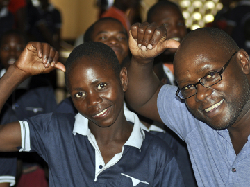 A deaf Tanzanian American and a student in a deaf unit in Tanzania signing their identical &quot;sign names.&quot; Image/Amabilis Batamula