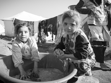 Syrian girls wash clothes outside their tent in the displaced persons camp in Atmeh, Syria in 2013.
