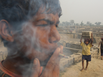 A 15-year-old child laborer, smokes a bidi (leaf-rolled tobacco cigar) while working in a brick factory at Ghanashyampur village in Murshidabad, 350 km north of Kolkata, India.