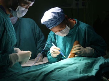 Dr. Shankar Man Rai taking a skin graft in a Nepal operating room.