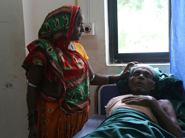 Urmila Devi Poddar stands beside her husband Ladayan Poddar, who accidentally touched a live wire and suffered burns so severe that his right arm had to be amputated. 
