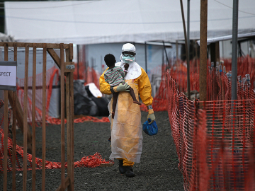 A Médecins Sans Frontières health worker carries a child suspected of having Ebola in the MSF treatment center on October 5, 2014 in Paynesville, Liberia.