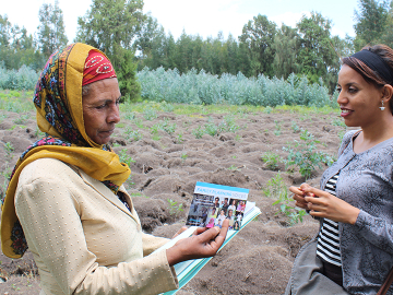 A worker with the PHE-Ethiopia Consortium, right, shares information with a schoolteacher in the rural Bale-Eco region.