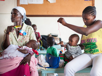 Caretakers in Kenya playing with children in a health facility waiting room (using toys made from locally available materials).