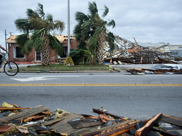 A bicyclist rolls past a devastated Panama City, Florida streetscape after Hurricane Michael. (Image: Brendan Smialowski /AFP/Getty Images)