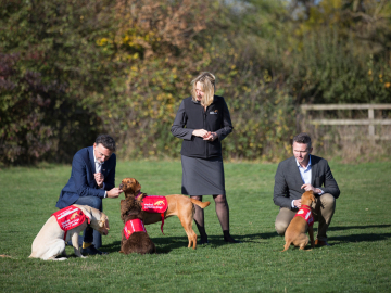 Principal investigator Steve Lindsay (left), Medical Detection Dogs CEO Claire Guest and London School of Hygiene and Tropical Medicine Professor James Logan share a moment with the remarkable sniffers. (Image: Durham University/Medical Detection Dogs/LSHTM)