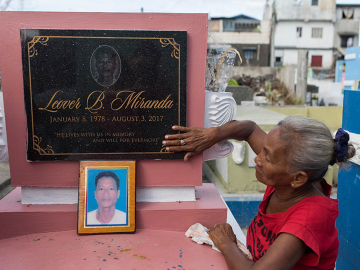 Elvira Miranda lovingly touches the grave of her son, Leover, killed in the Philippines drug wars. Image by Amanda Mustard