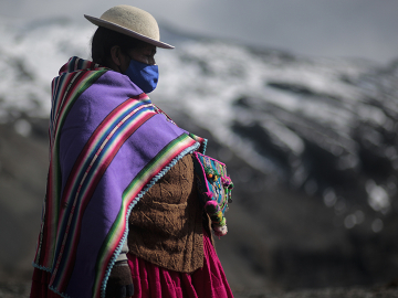 A woman wearing a mask watches a traditional ceremony in La Paz, Bolivia on September 21, 2020. Image: Gaston Brito/Getty Images