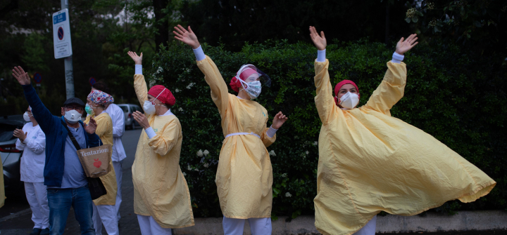 Several health care workers wearing face masks and yellow protective suits acknowledge applause outside the Hospital de Barcelona on April 13, 2020 in Barcelona, during a national lockdown to prevent the spread of the COVID-19 disease. 