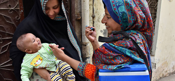 A woman gives a polio vaccine to baby.