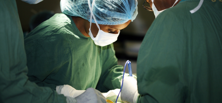 Closeup of a surgeon in green scrubs and her assistants operating on a patient. Universal Images Group Getty
