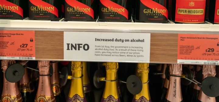 A notice is posted about a rise in duty for alcoholic beverages, between two rows of champagne bottles on store shelves, August 4, 2023 at a Sainsbury's Market in London, England. Robert Nickelsberg/Getty