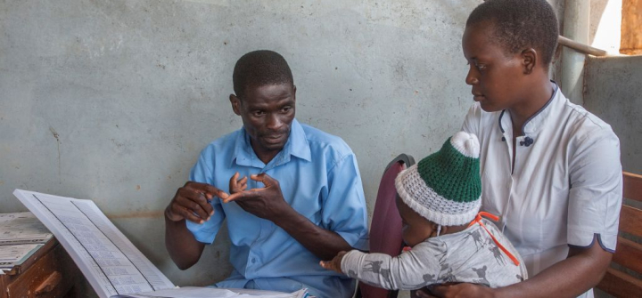 A health surveillance assistant talks to a mother at a malaria vaccine screening table in Lilongwe, Malawi, April 23, 2019.