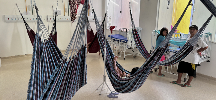 Yanomami Indigenous people rest in traditional blue and white hammocks used in lieu of hospital beds.