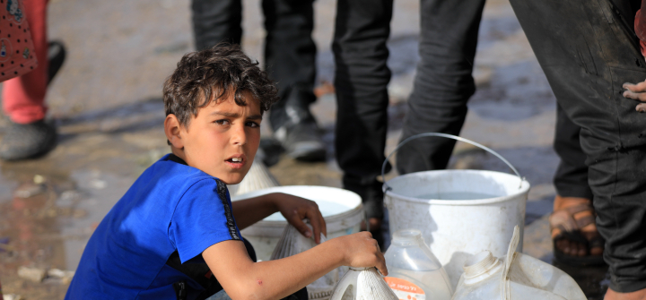 A Palestinian child wearing a blue shirt waits in line for clean water in Rafah, Gaza, on March 16. 