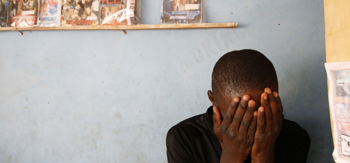 A young man hiding his face in his hands.