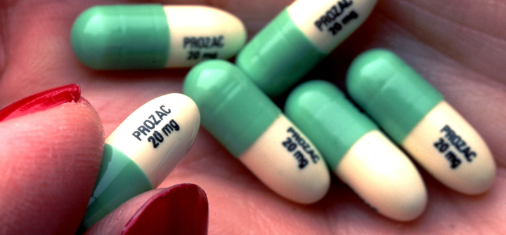 A person holds Prozac tablets in their palm.