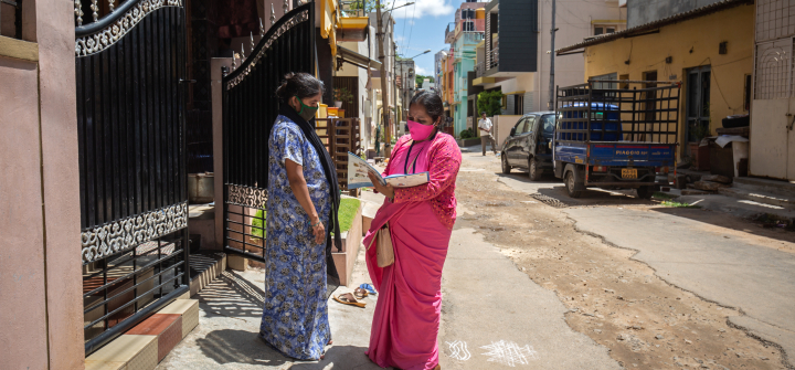 Sunitha, an Accredited Social Health Activist (ASHA) checks on a pregnant woman outside her house on May 18, 2021, in Mysuru, India.