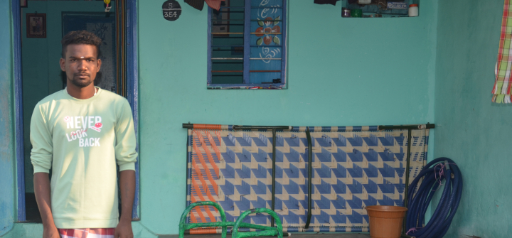 Muthukutti, a 23-year-old man from Surangudi, India, stands outside his home.