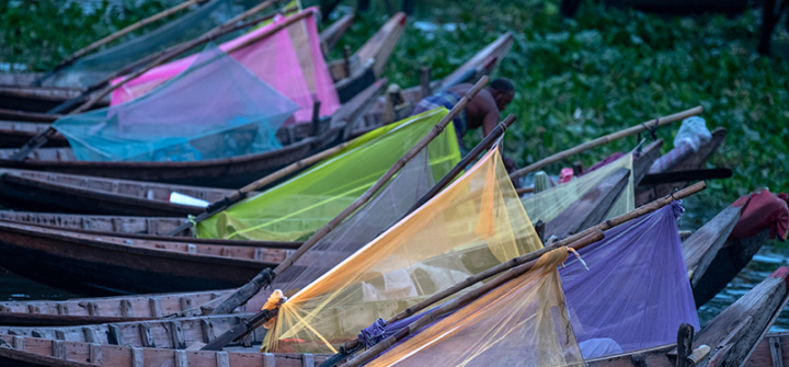 Boatmen sleep inside colorful mosquito nets on their boats on the Buriganga River in Dhaka, Bangladesh.