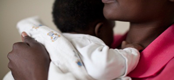 A mother in Rwanda holds her child while listening to a nutrition nurse. 