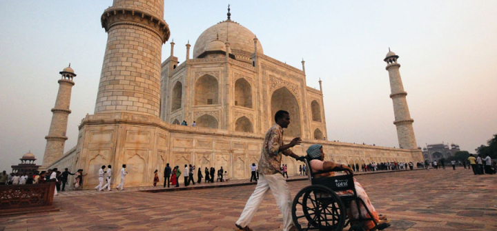 A man pushes a woman in a wheelchair at the Taj Mahal in Agra, India.