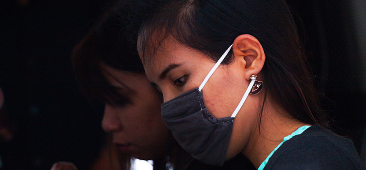 Young Thai girl with mobile and surgical mask. 