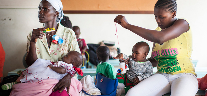 Caretakers in Kenya playing with children in a health facility waiting room (using toys made from locally available materials). 