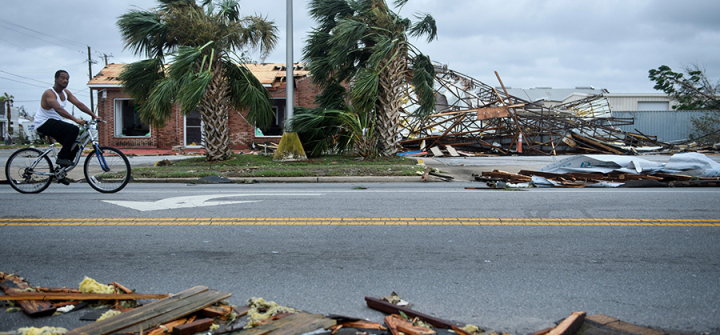 A bicyclist rolls past a devastated Panama City, Florida streetscape after Hurricane Michael. (Image: Brendan Smialowski /AFP/Getty Images)